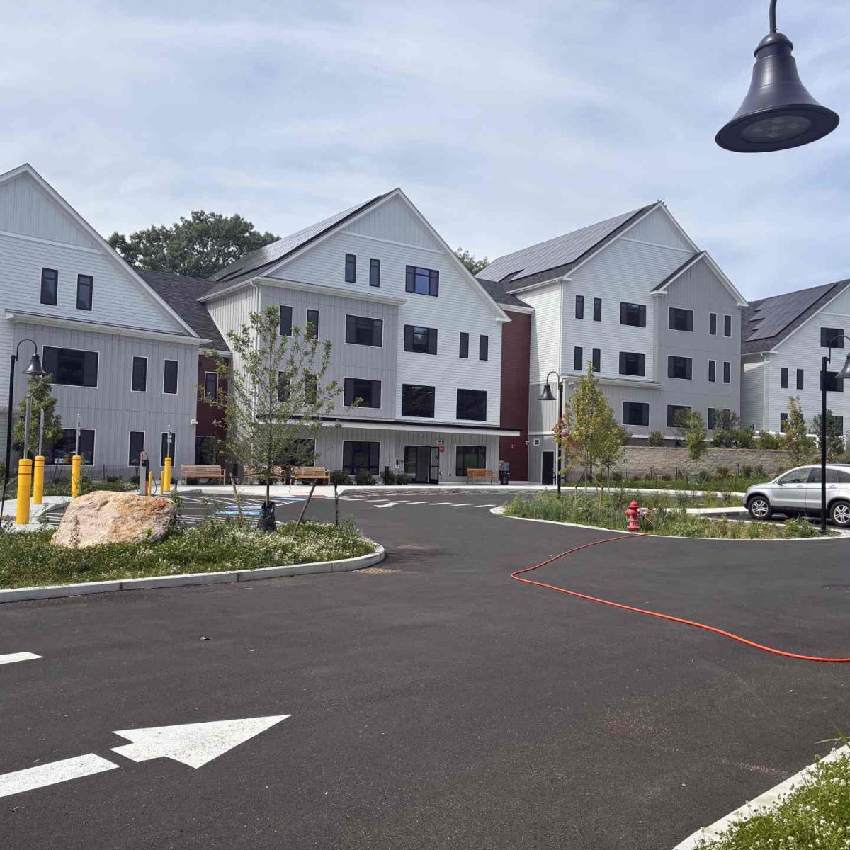 Multiple gabled apartment buildings at McManus Manor senior apartments with solar panels, a paved driveway, and landscaped grounds