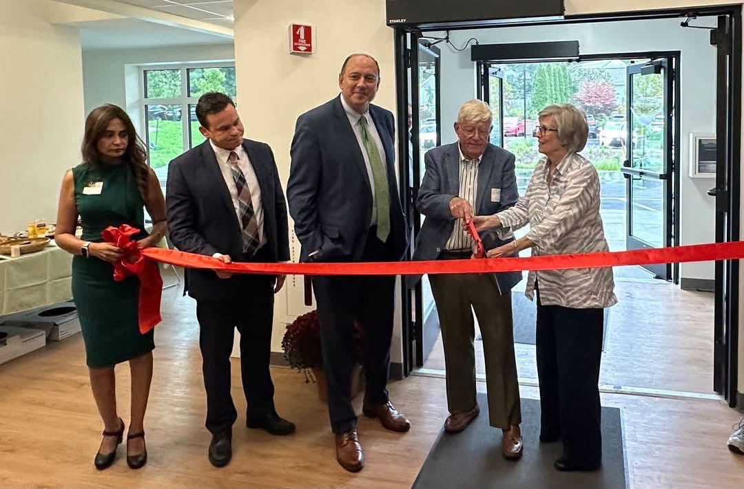 Five people cut a red ribbon together at the entrance of McManus Manor senior apartments
